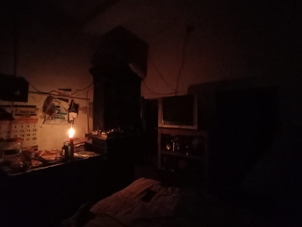 Dunkler Innenraum während eines Stromausfalls, nur schwach von einer Kerze beleuchtet.