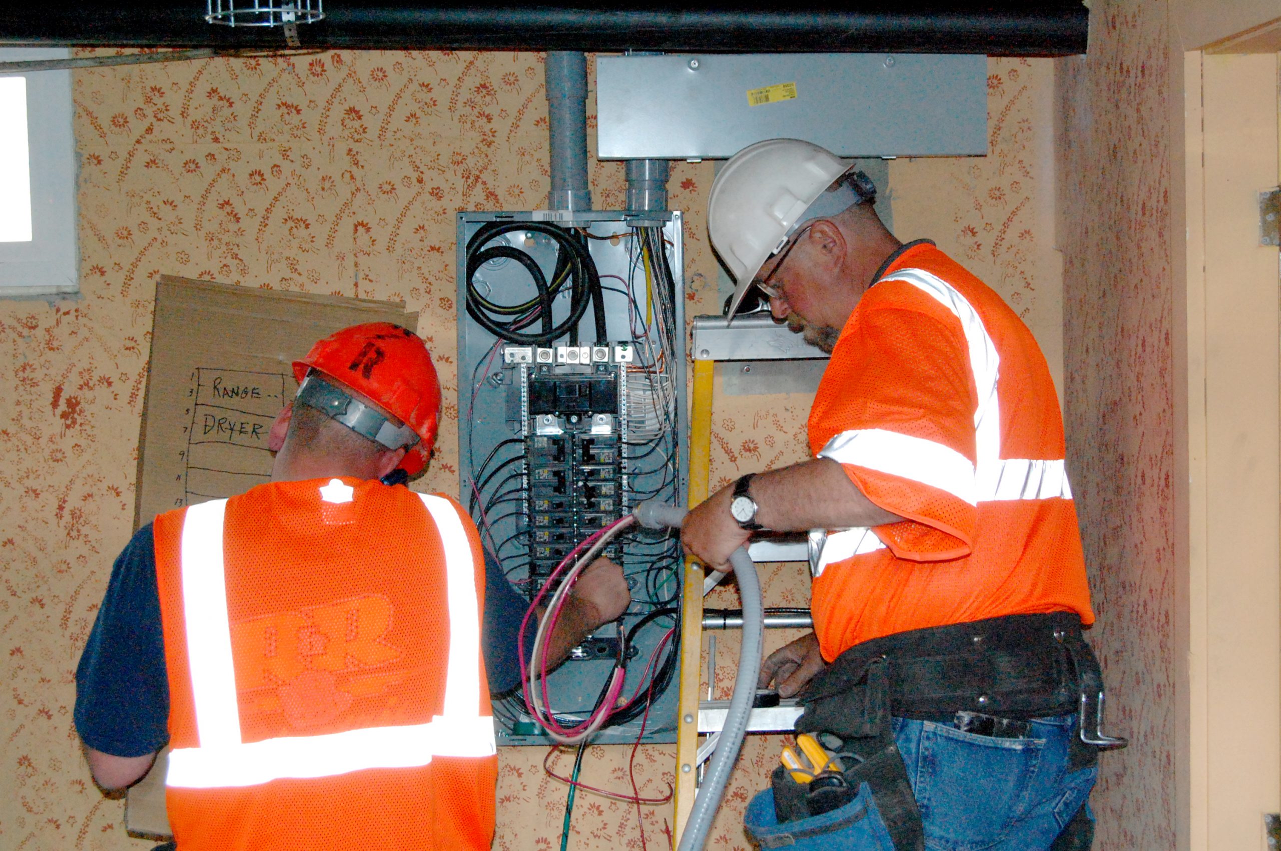 Handwerker installieren einen neuen Sicherungskasten bei einer Gebäudemodernisierung
