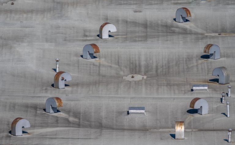 Breite Betonwand mit mehreren verteilten Wandleuchten und sichtbaren Lichtfeldern.