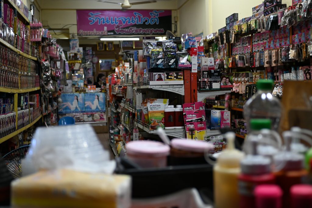 Schmaler Laden mit dicht gefüllten Warenregalen und heller Allgemeinbeleuchtung.