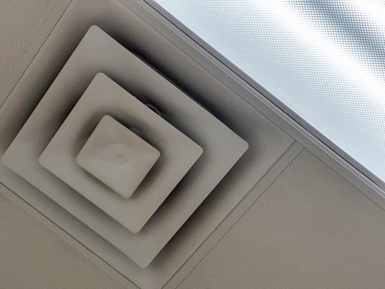 Regelmäßiges Raster einer abgehängten Decke mit Leuchtenfeldern und Lüftungsauslässen