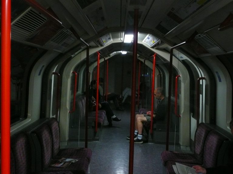 Innenraum eines U-Bahn-Wagens, der bei abgeschalteter Hauptversorgung nur durch Notlicht beleuchtet wird.