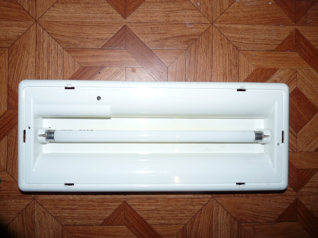 Geöffnete Notleuchte mit Leuchtstoffröhre, Reflektor und elektrischen Bauteilen.