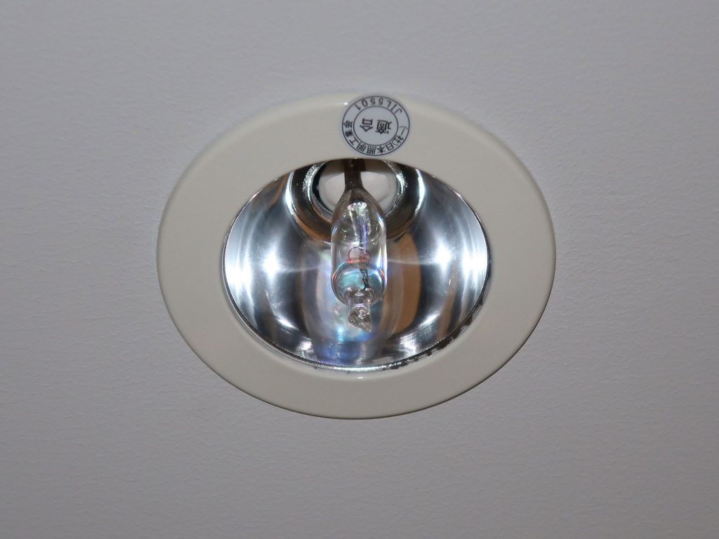 Runde deckenmontierte Notleuchte mit Halogenlampe in einem Gebäude.