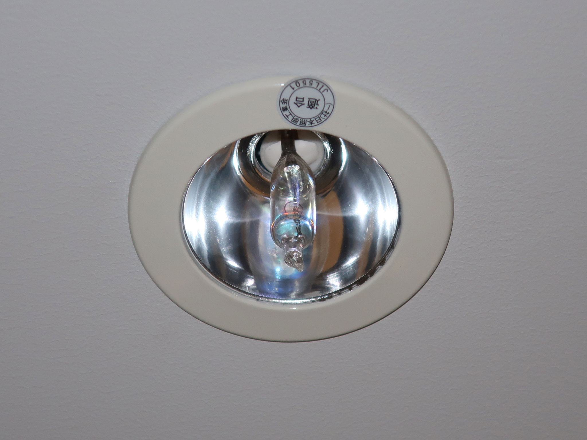 Runde deckenmontierte Notleuchte mit Halogenlampe in einem Gebäude.