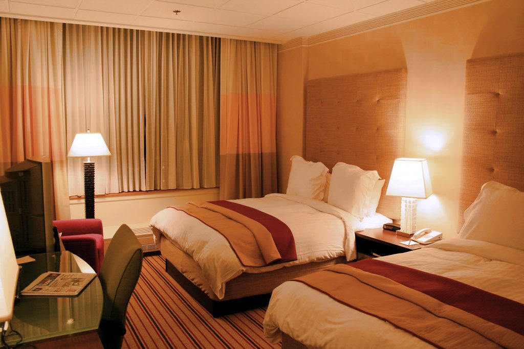 Hotelzimmer mit Doppelbett, Sitzbereich und mehreren Leuchten für unterschiedliche Raumzonen.