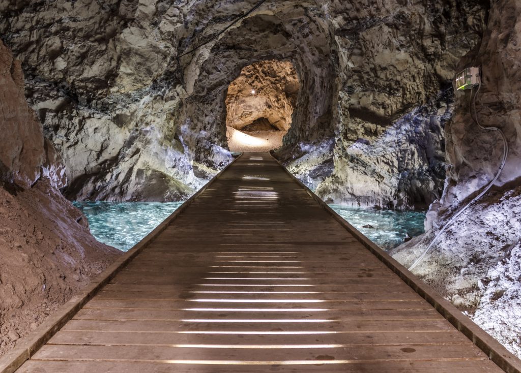 Mit einzelnen Leuchten markierter Weg durch einen dunklen Tunnel im Kalkbergwerk