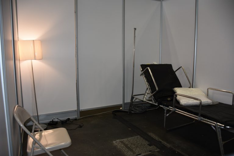 Helles Patientenzimmer mit Krankenhausbetten, medizinischer Ausstattung und Deckenbeleuchtung.