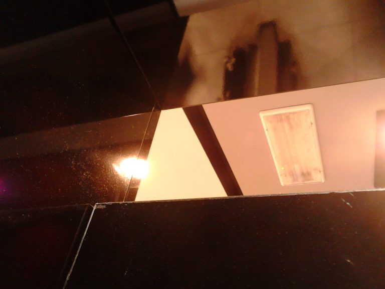 Rechteckige wandmontierte Notleuchte mit diffuser Abdeckung in einem Innenraum.