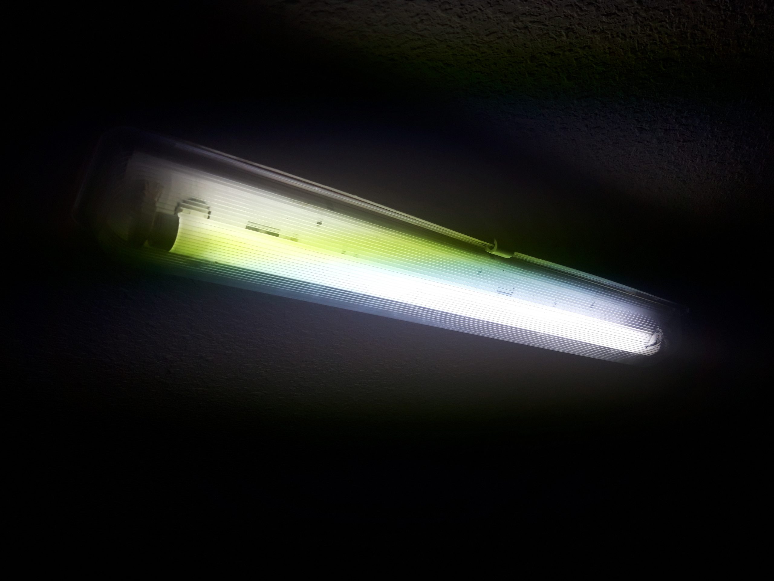 Längliche Fluoreszenzleuchte mit transparenter Abdeckung an einer Raumdecke