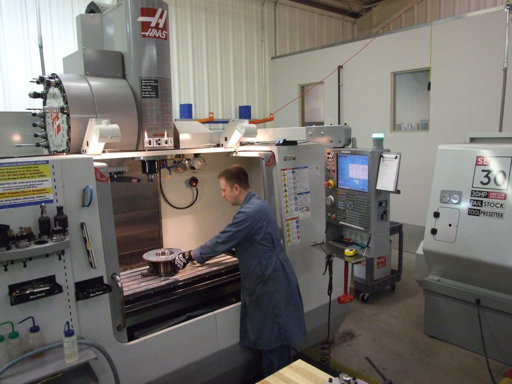 Werkstattarbeitsplatz mit Werkzeugmaschine, Werkbank und technischer Beleuchtung.