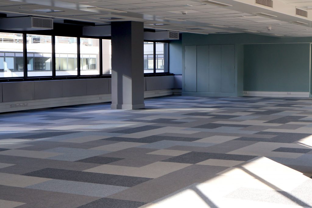 Leere Bürofläche mit breiten Fensterfronten und hellem Tageslicht