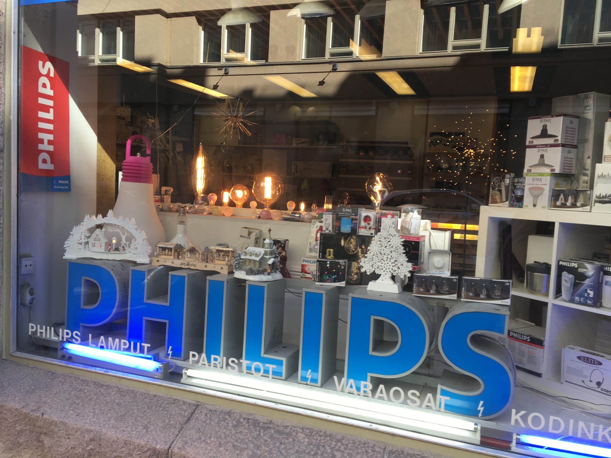 Schaufenster mit dekorativ angeordneten Leuchtmitteln und beleuchteter Produktpräsentation.