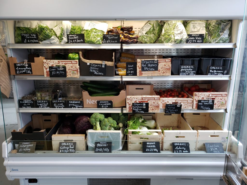 Obst- und Gemüseabteilung mit farbigen Waren, offenen Regalen und heller Verkaufsbeleuchtung.