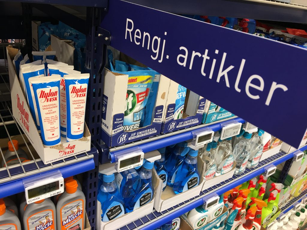 Supermarktgang mit hohen, vollständig bestückten Warenregalen auf beiden Seiten.
