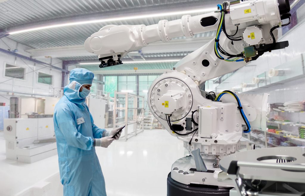 Fachkraft arbeitet an einer Industrieanlage in einem hellen, geschlossenen Reinraum.