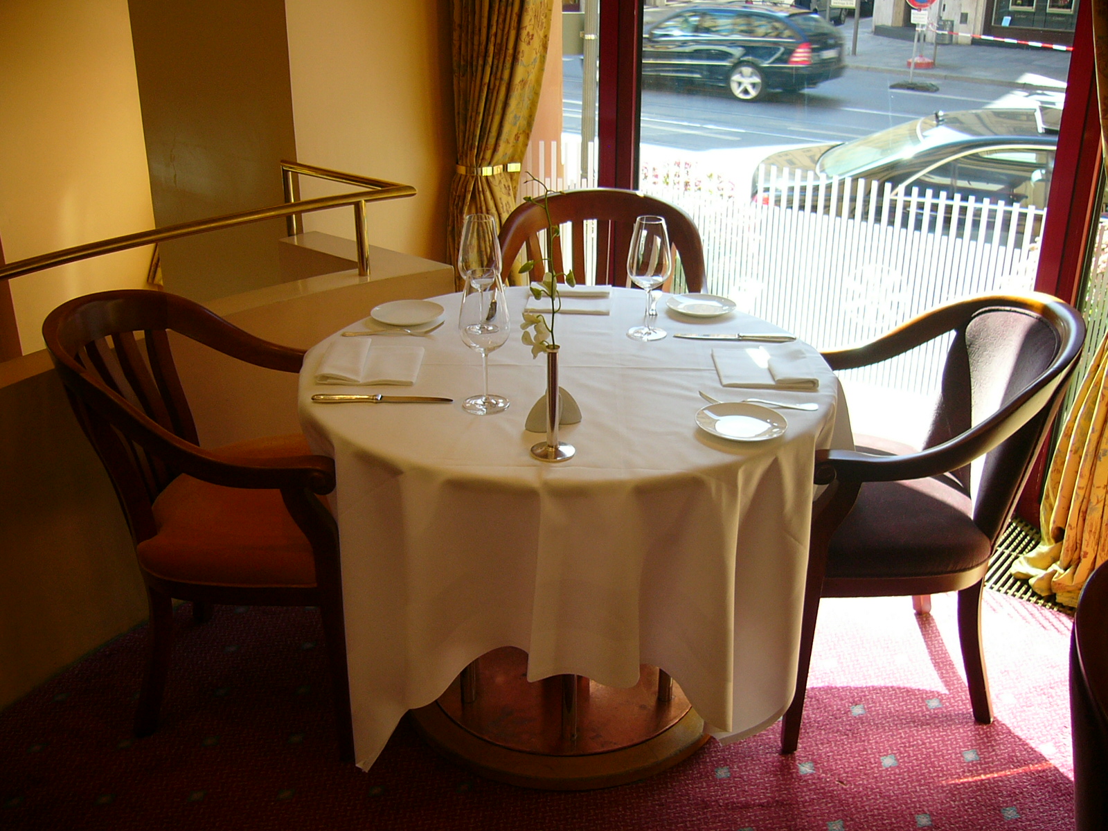Gedeckter Tisch in einem Restaurant mit Gläsern, Geschirr und gerichteter Beleuchtung.