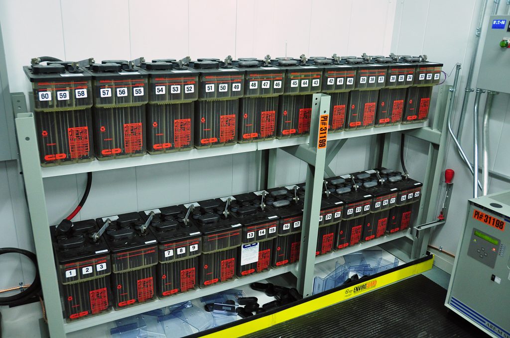 Mehrere Reihen großer Bleiakkumulatoren in einem technischen Batterieraum.